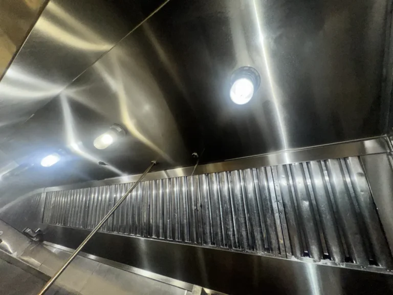 Commercial kitchen hood after cleaning, with stainless steel canopy and baffle filters installed