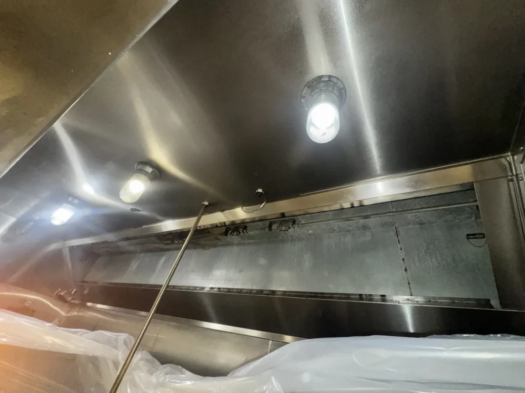 Grease residue inside a commercial kitchen hood with the baffle filters removed before cleaning