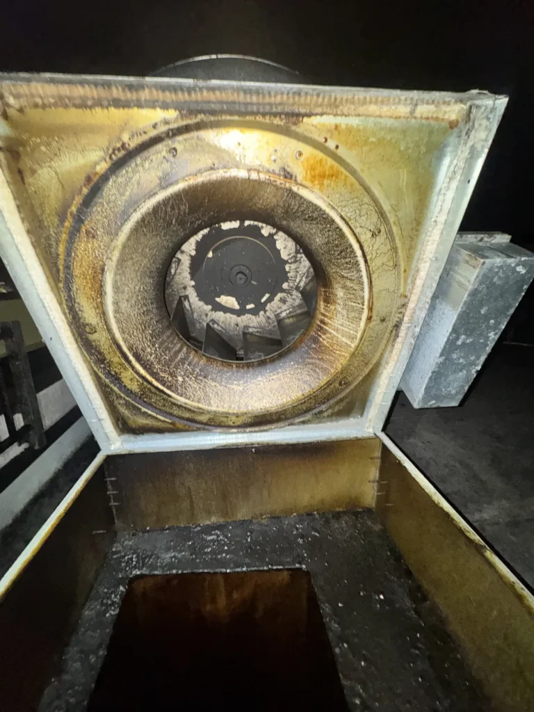 Grease deposits inside a kitchen exhaust fan before cleaning