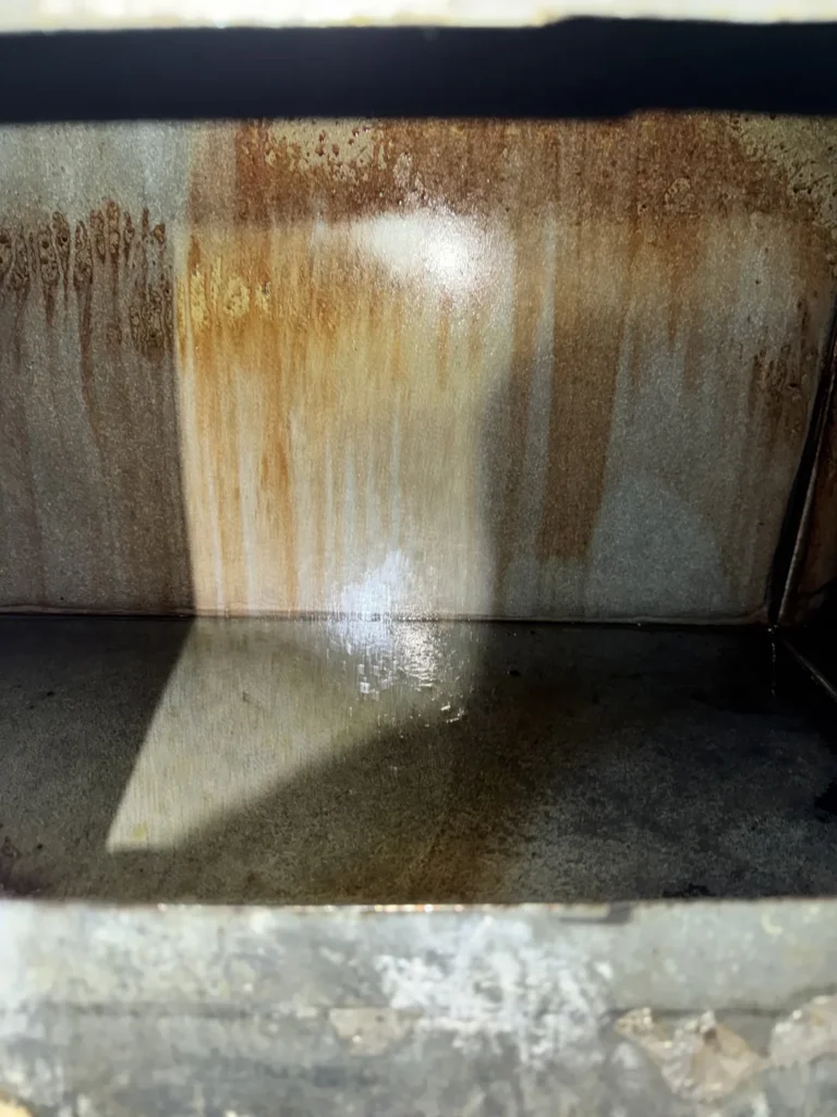 Grease streaks on an accessible exhaust duct wall before cleaning